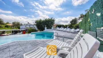 Privézwembad met meerdere witte kunststof ligstoelen op een betegeld terras bij Villa Geolouk in Spanje.