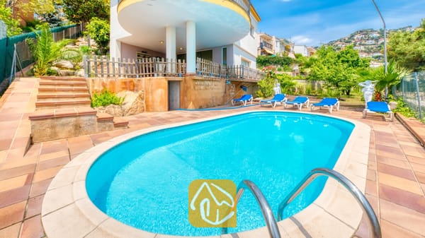 Zwembad met een ovale vorm en helderblauw water bij Villa Valentina in Spanje, omringd door een betegeld terras, blauwe ligbedden, stenen treden en tuinarchitectuur.