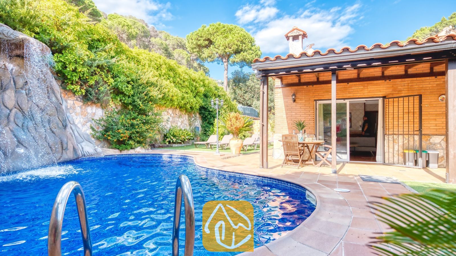 Privézwembad met een natuurstenen waterval bij Villa Alba, met een bakstenen terras, houten eermeubilair en een pannendak.