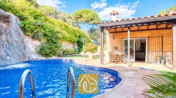 Privézwembad met een natuurstenen waterval bij Villa Alba, met een bakstenen terras, houten eermeubilair en een pannendak.