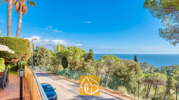 Kustpanorama vanaf Villa Santa Cristina met een geplaveide weg omzoomd door pijnbomen en een helder uitzicht op de blauwe zee in de verte.