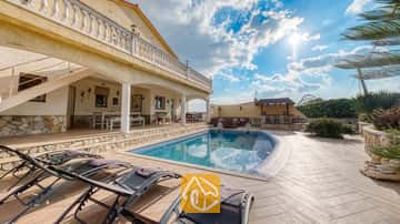 Privézwembad met ligstoelen op het betegelde terras van Villa Madonna in Spanje, voorzien van een overdekt terras en stenen muren onder een zonnige hemel