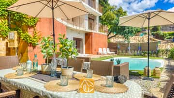 Buiten eettafel, gedekt met geweven placemats, glazen en potten met citroenplanten bij Villa Sunny Beach, met uitzicht op een zwembad en terras.